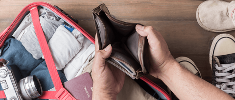 an opening empty wallet over a packed suitcase