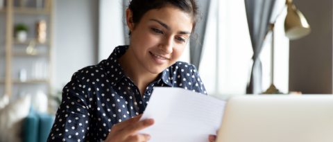 Woman sitting in front of her computer while reviewing a paper document