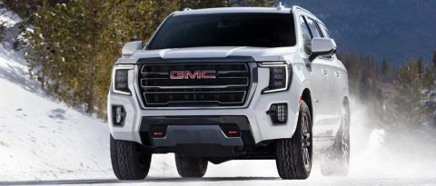 Winterized white GMC SUV driving down a mountain road